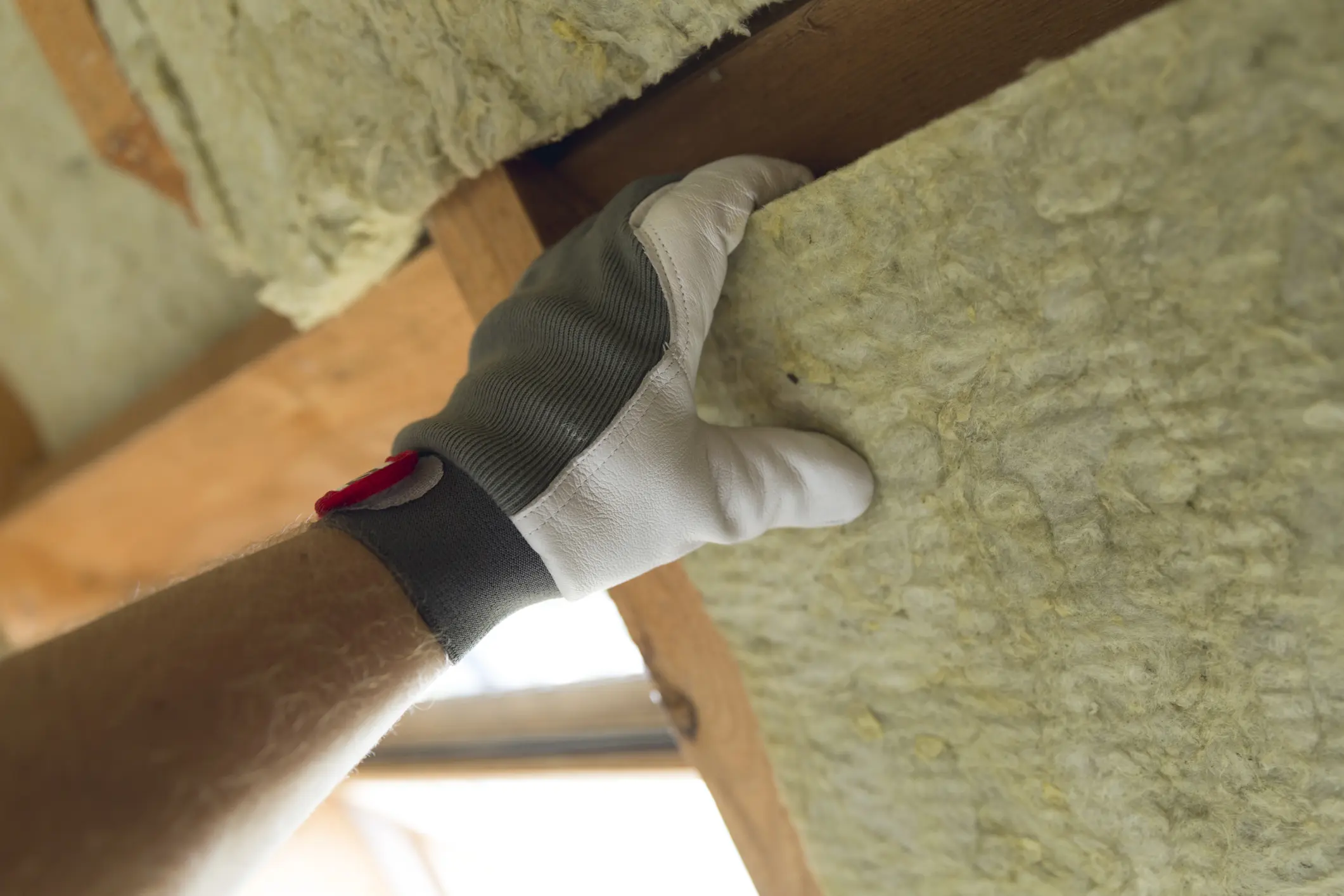 Worker installing attic insulation blanket for energy-efficient weatherization