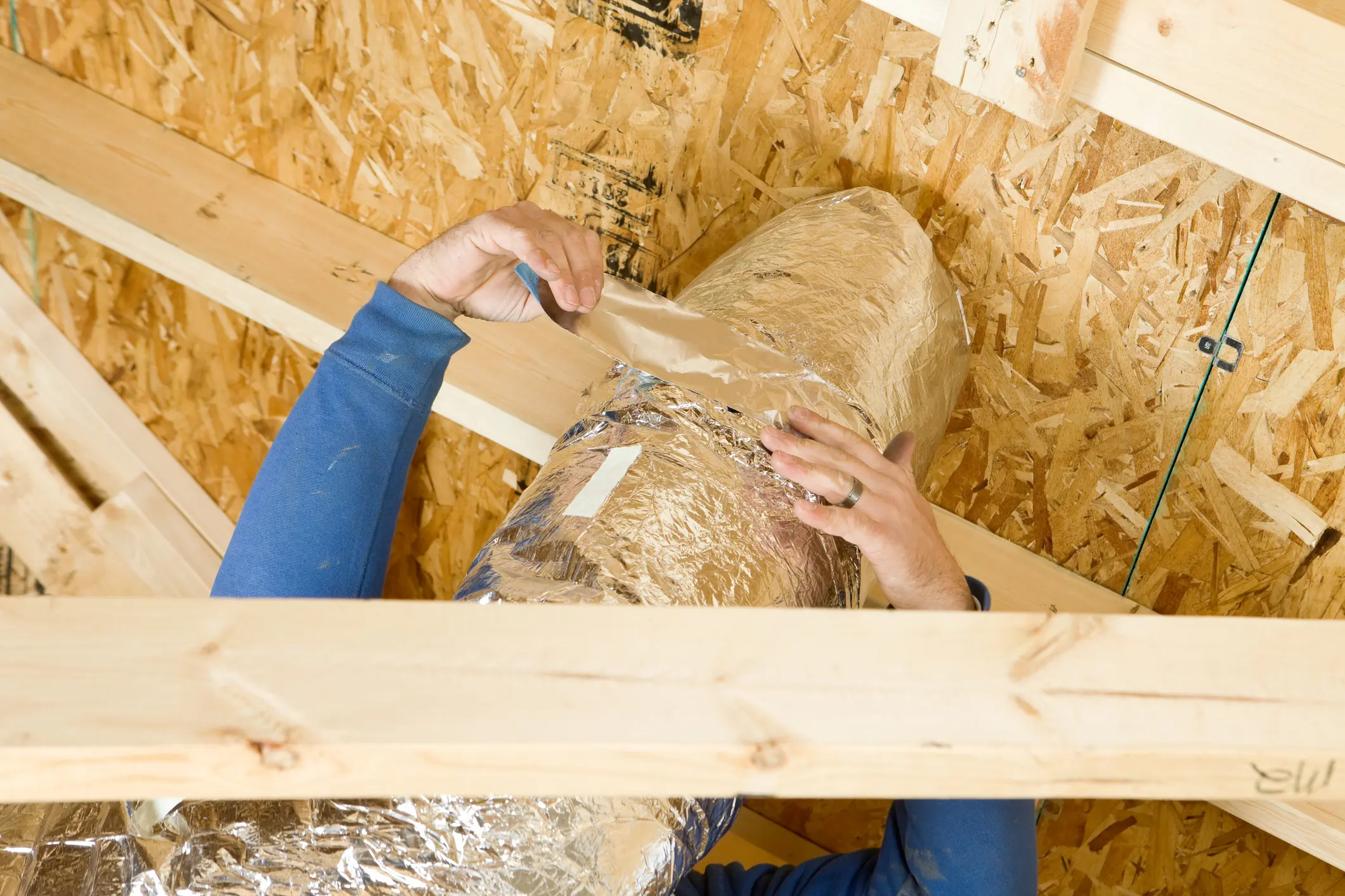 Worker Insulating an Attic Vent Duct